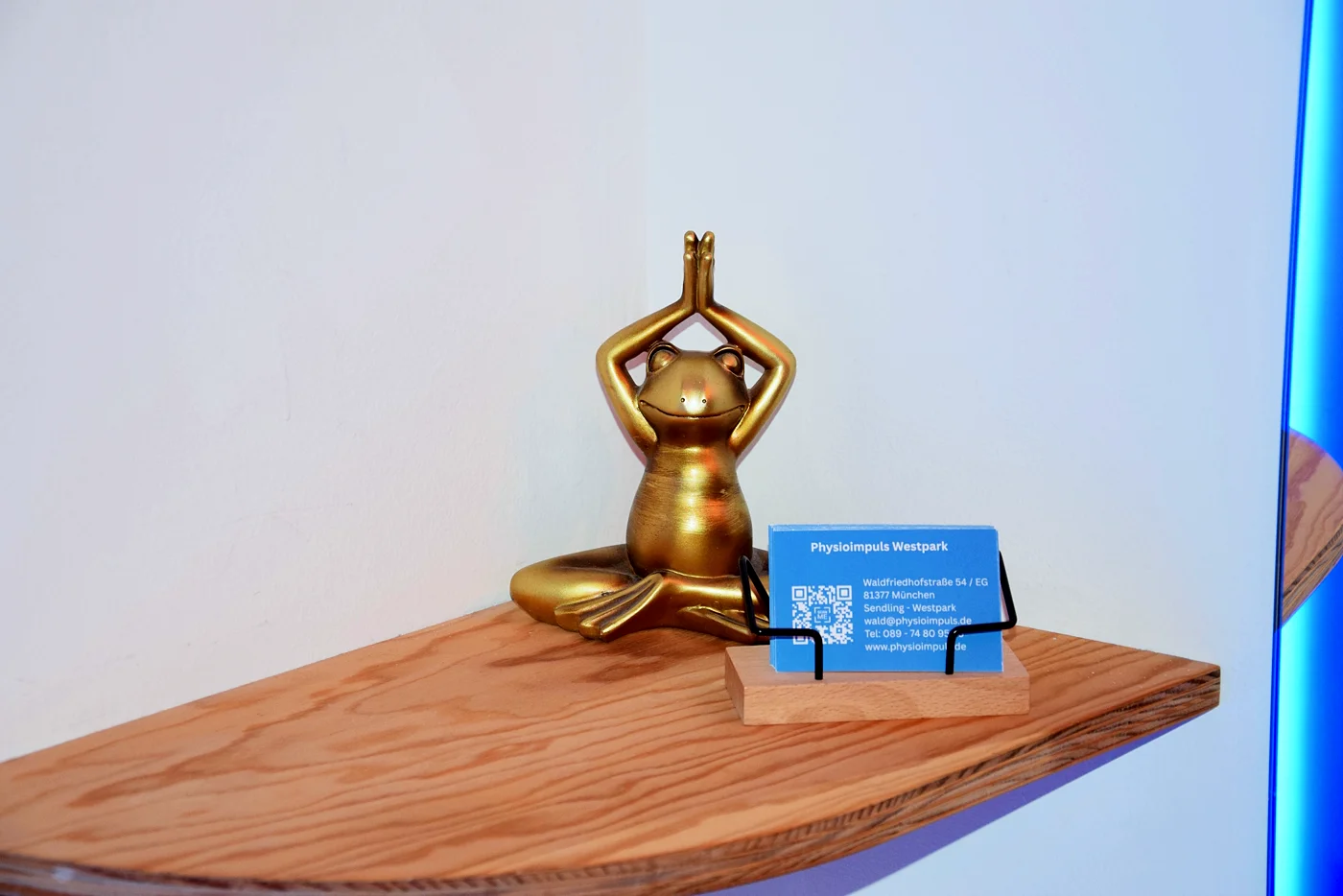 Goldene Frosch-Figur neben der Visitenkarte von Physioimpuls Westpark
